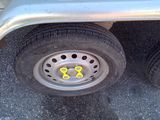 a silver trailer with two wheels that have yellow numbers on them