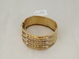 a close up of a gold bracelet on a white surface
