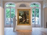 a painting on display in a large room with a statue in front of it