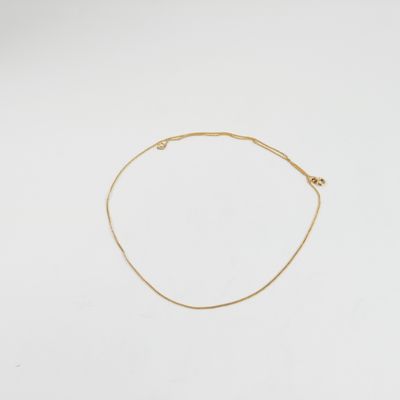 un bracelet en chaîne dorée orné d'une petite perle sur fond blanc