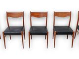 set of four dining chairs with black leather seats on a white background