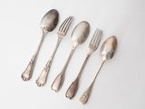 six spoons and a fork are lined up on a white surface