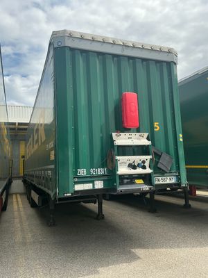 deux semi-remorques verts garés l'un à côté de l'autre sur un parking