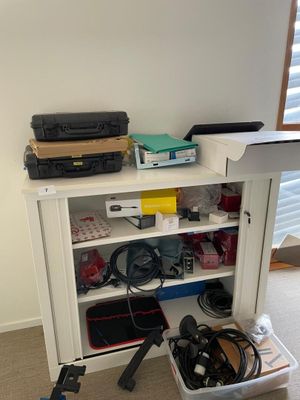 a white bookcase with a bunch of electronics on top of it