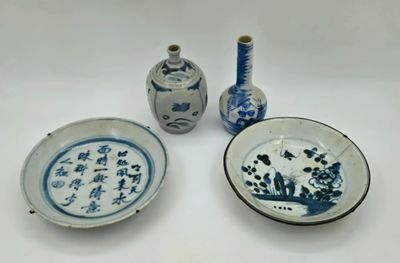 trois assiettes bleues et blanches et deux vases posés sur une table