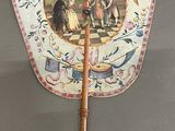 a small fan with a painting on it on a table