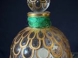 a glass jar with a gold and green decoration on it