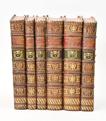 six vieux livres sont alignés sur une surface blanche