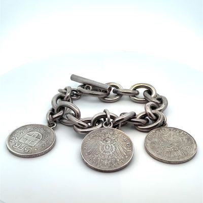 un bracelet en argent orné de pièces, posé sur un fond blanc