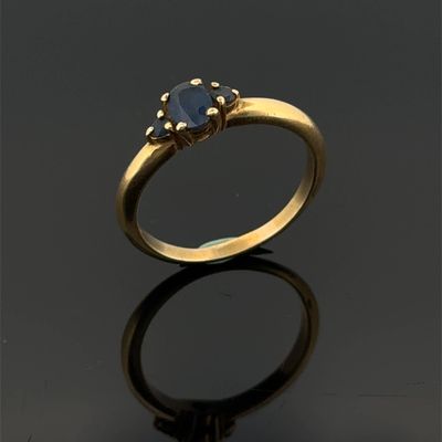 gros plan d'une bague en or avec une pierre en saphir