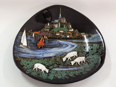 a black plate with a picture of sheep and a boat on it