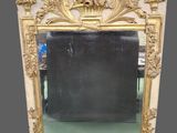 un miroir richement sculpté, avec un cadre doré, posé sur un sol vert
