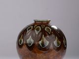 un vase marron et vert posé sur une surface blanche