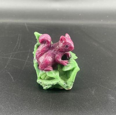 une petite figurine représentant un écureuil rose posé sur une feuille