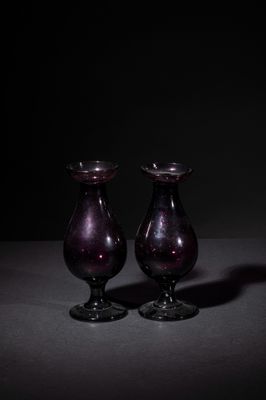 pair of purple glass vases sitting on top of a table