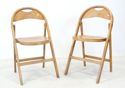 une paire de chaises pliantes en bois adossées à un mur blanc dans une pièce