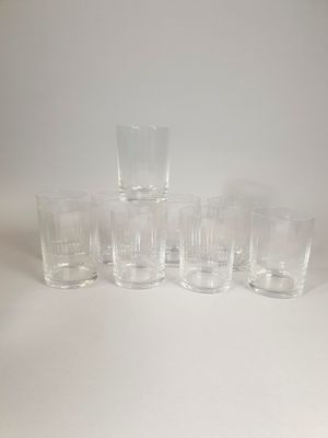 six clear glass tumblers lined up on a white surface