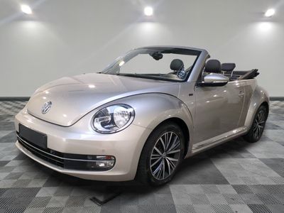 une photo d'une Volkswagen Coccinelle décapotable argentée garée sur un sol à damier