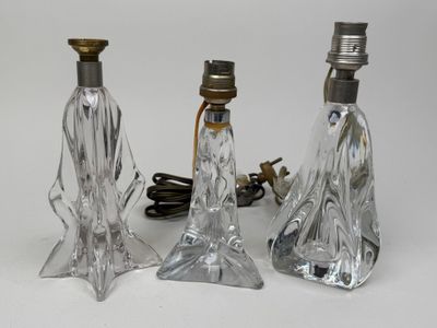 trois lampes en verre transparent posées les unes à côté des autres sur une surface blanche