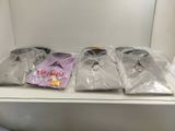 three shirts in plastic bags sitting on a shelf