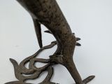 a bronze statue of a bird on a branch
