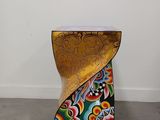 an image of a gold stool with a colorful design on it