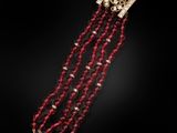 un gros plan sur un bracelet en perles rouges muni d'un fermoir doré