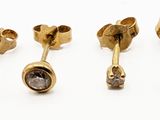 trois paires de boucles d'oreilles en or et diamants posées sur un fond blanc