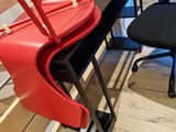 une valise rouge posée sur une chaise à côté d'une chaise noire