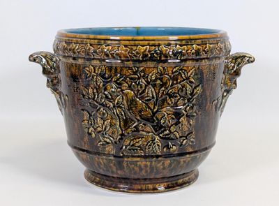 un vase brun et bleu posé sur une surface blanche