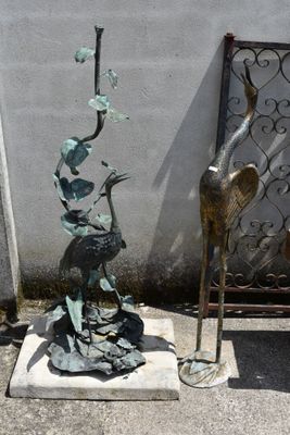 a statue of a bird sitting on top of a base next to a statue of a bird