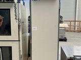 un homme debout devant une machine dans une usine