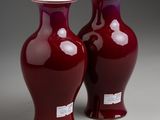 pair of red vases sitting on top of a white table