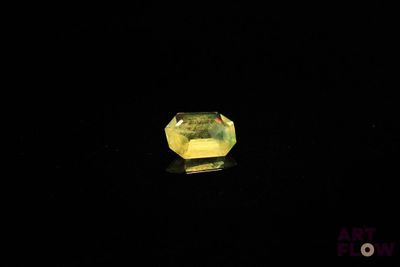 a yellow diamond on a black surface with a black background