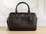 a brown coach purse sitting on top of a wooden table