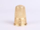 a gold thimble that is sitting on a white surface