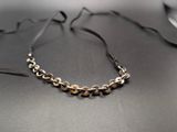 silver and gold chain necklace on a black table with a glass of water in the background