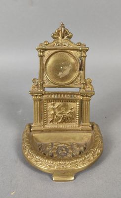une horloge dorée posée sur un socle, sur une surface blanche