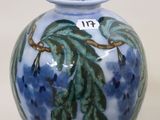 a blue vase with green leaves on it on a white background