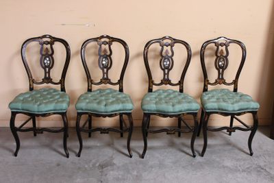 Quatre chaises sont alignées contre un mur dans une pièce.