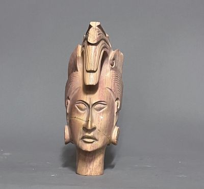 une sculpture en bois représentant une tête surmontée d'un oiseau