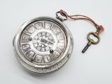 une montre de poche en argent à laquelle est attachée une clé