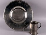 a silver plate and a silver cup next to each other