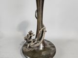 a silver vase with a dragon on it sitting on a table