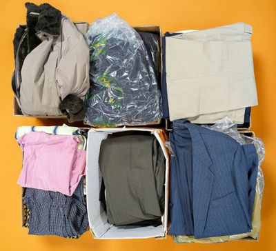 a box full of clothes and a cat sitting on top of it