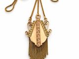 an image of a gold necklace with a long chain and a pendant with a design on it