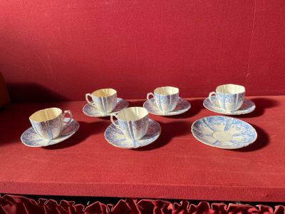 six tasses et soucoupes posées sur une table rouge