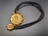 a necklace with a gold coin on a black cord