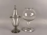 deux vases en verre transparent avec couvercle, posés sur une surface blanche