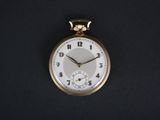 a gold pocket watch with a white face on a black background